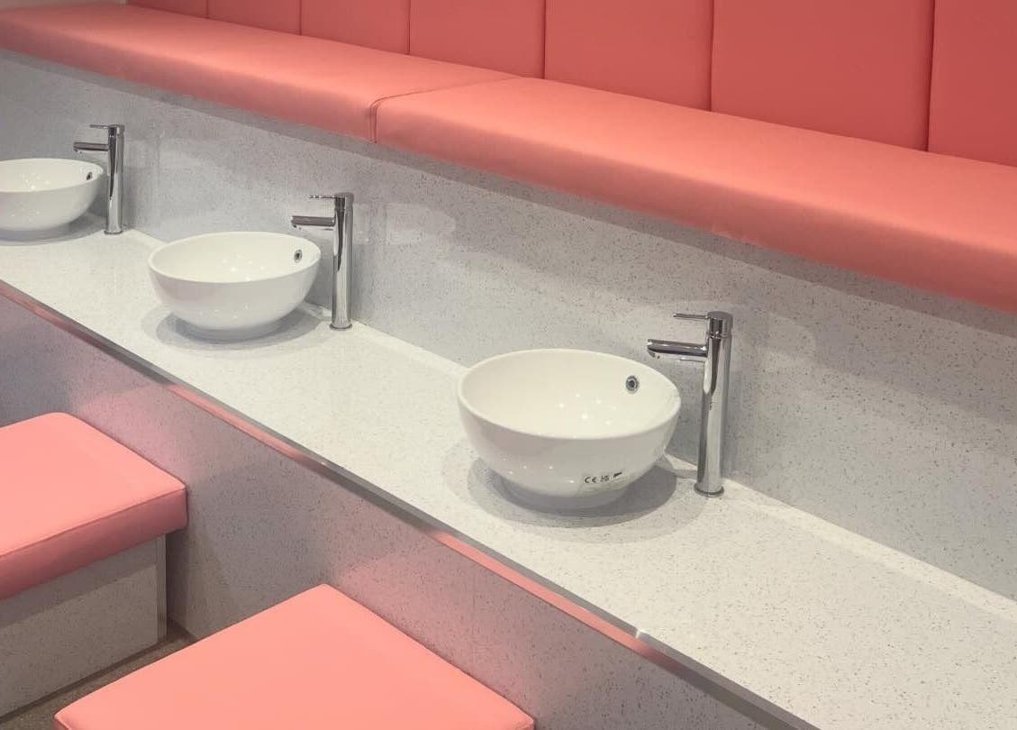 Elegant wash basin setup at Elysium Beauty Limited in Castletown, GB with pink seats and modern design.