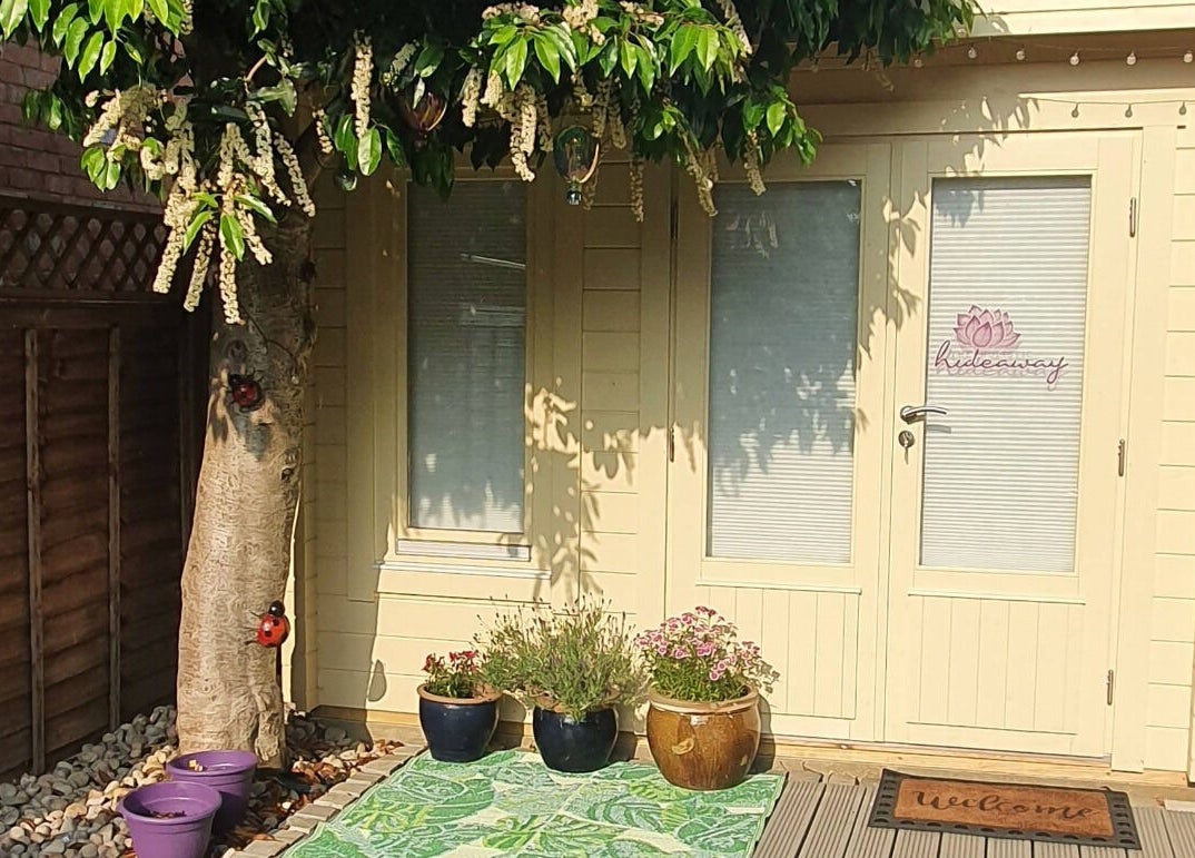 Charming entry to The Holistic Hideaway in Saint Neots, England, GB, adorned with potted plants under a lush tree.