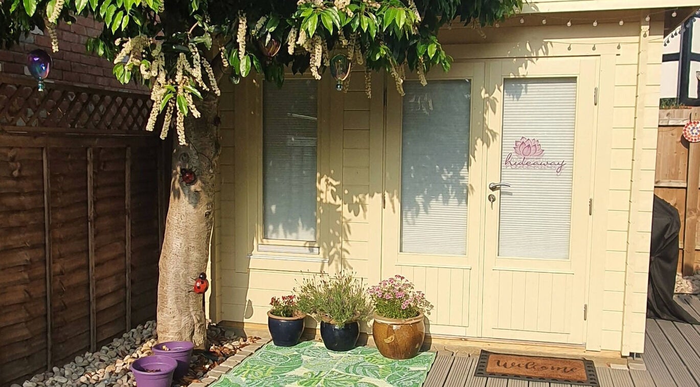 Charming entry to The Holistic Hideaway in Saint Neots, England, GB, adorned with potted plants under a lush tree.