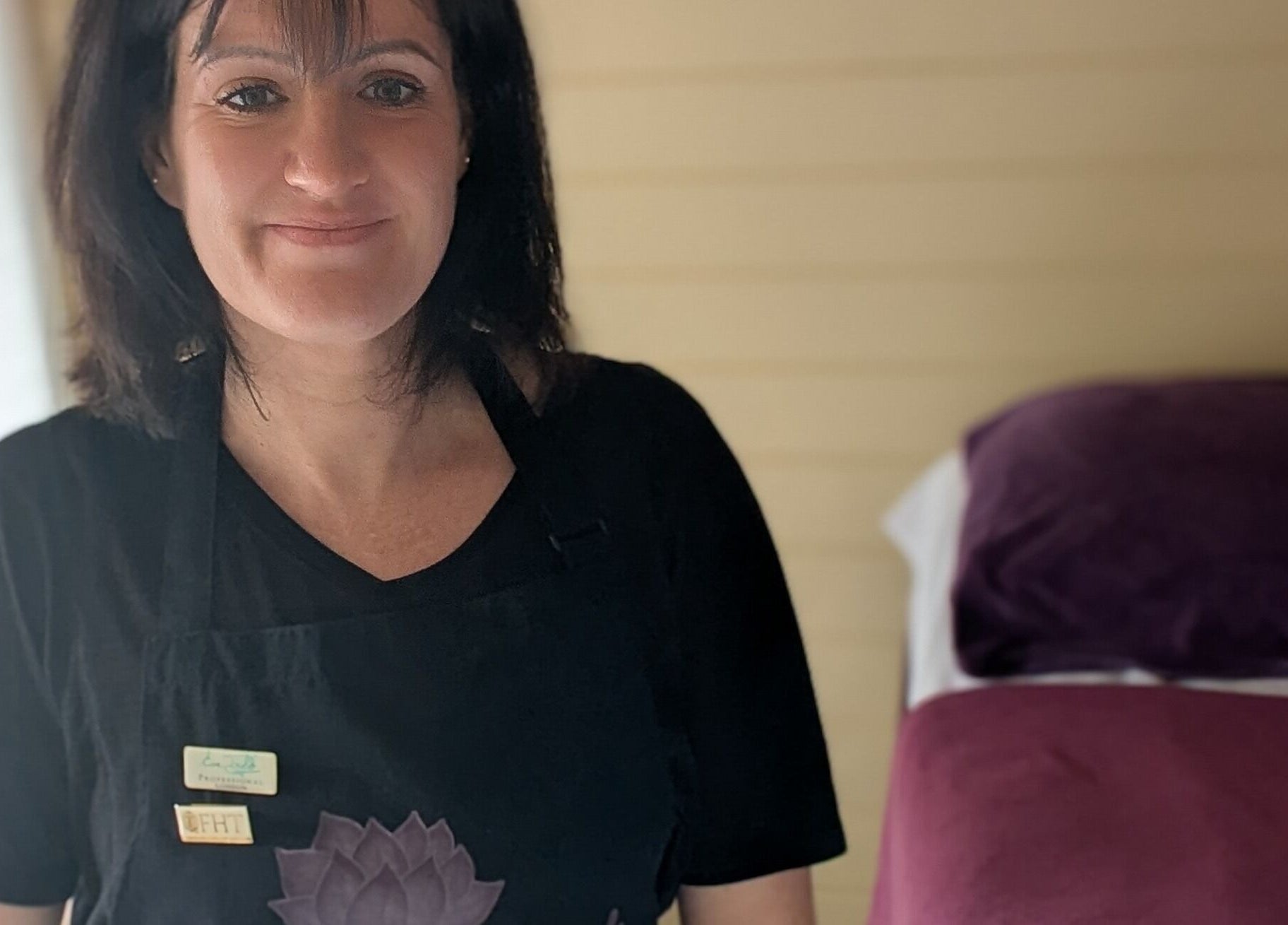 Friendly therapist at The Holistic Hideaway, Saint Neots, England, GB, with treatment table in the background.