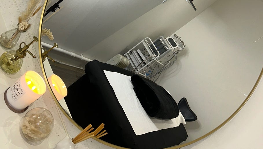 Elegant treatment room at Derma, Glasgow, Scotland, GB with cozy black bed, mirror, and ambient lighting.