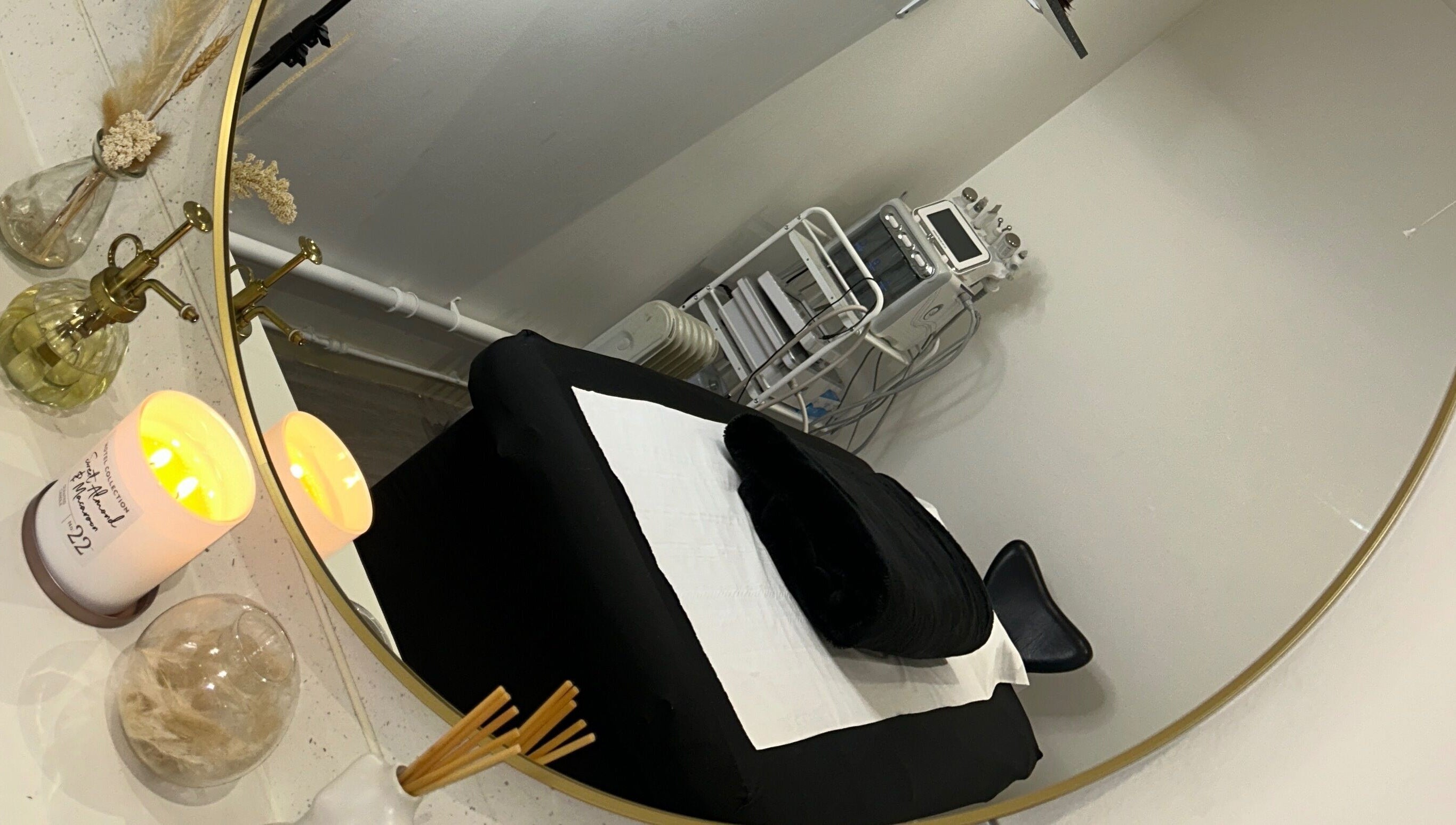 Elegant treatment room at Derma, Glasgow, Scotland, GB with cozy black bed, mirror, and ambient lighting.