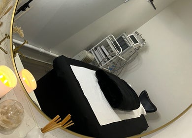 Elegant treatment room at Derma, Glasgow, Scotland, GB with cozy black bed, mirror, and ambient lighting.