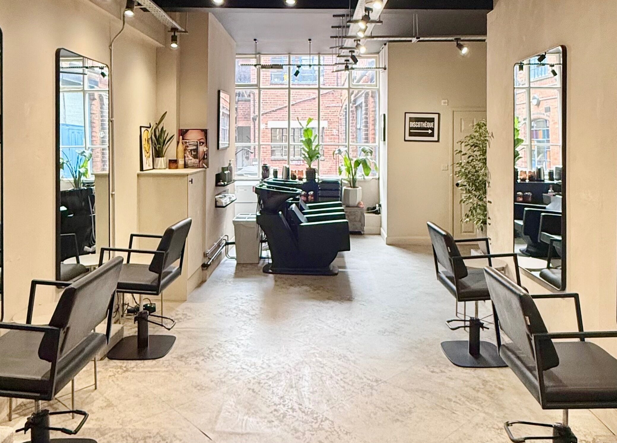 Modern salon interior at STORI, Birmingham, England, GB with sleek chairs and large mirrors.