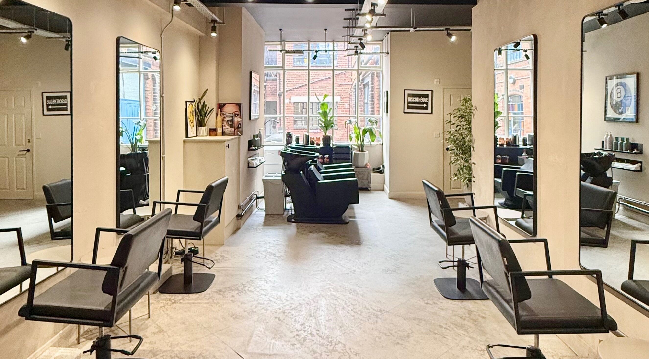 Modern salon interior at STORI, Birmingham, England, GB with sleek chairs and large mirrors.