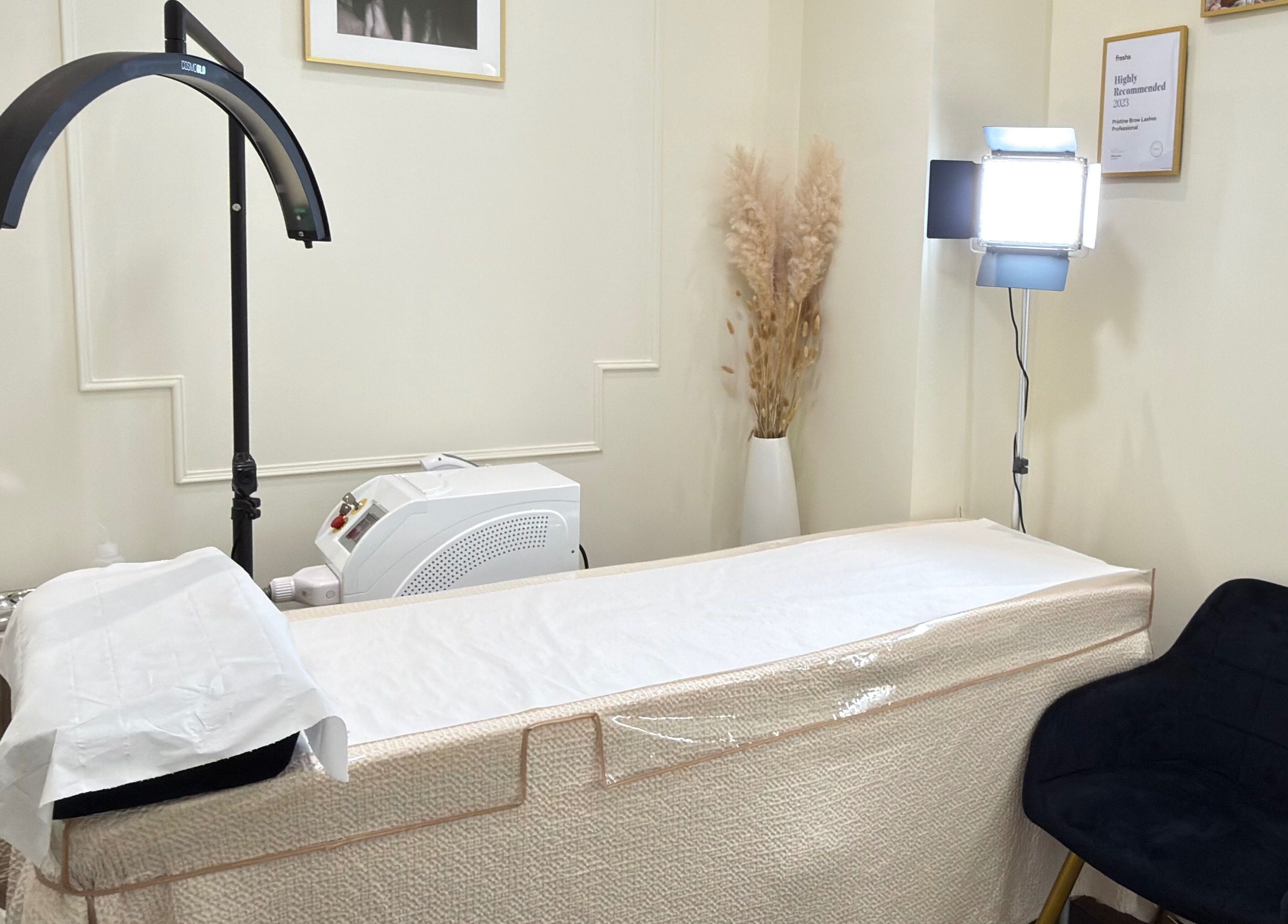 Elegant treatment room at Pristine BrowLashes Professional, London, England, GB, featuring a cozy chair and treatment bed.
