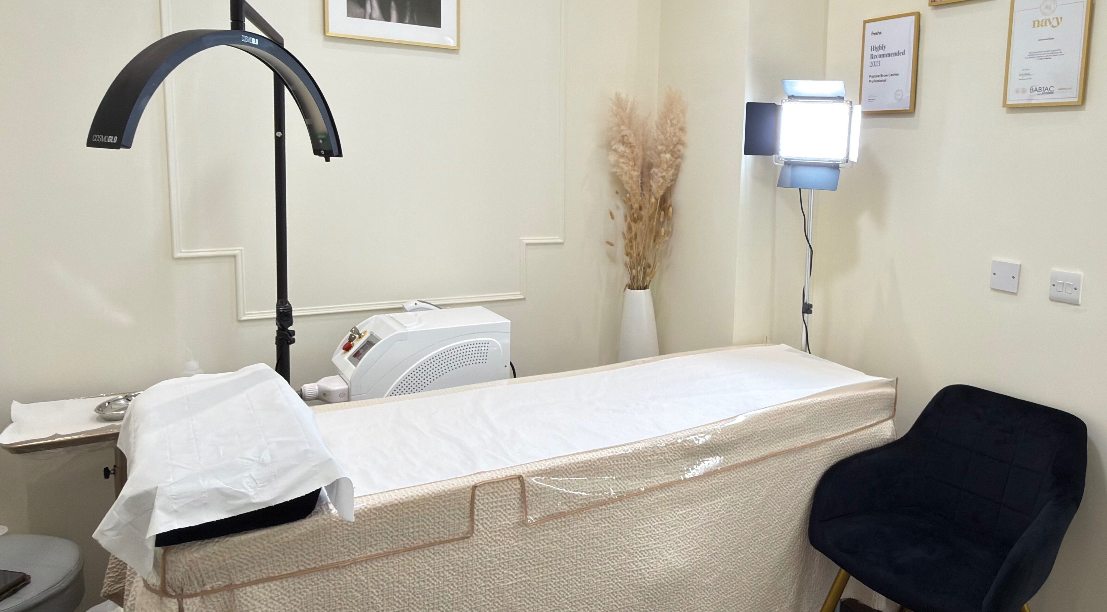 Elegant treatment room at Pristine BrowLashes Professional, London, England, GB, featuring a cozy chair and treatment bed.