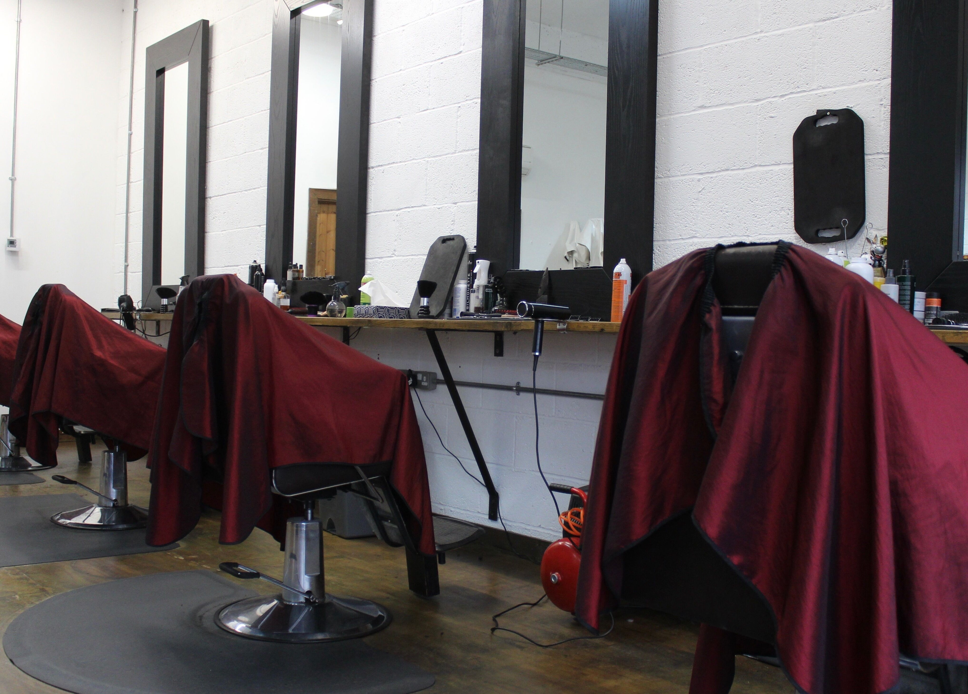 Interior of Lewis' Barbershop in Cambridge, England, GB showing stylish red-draped barber chairs.