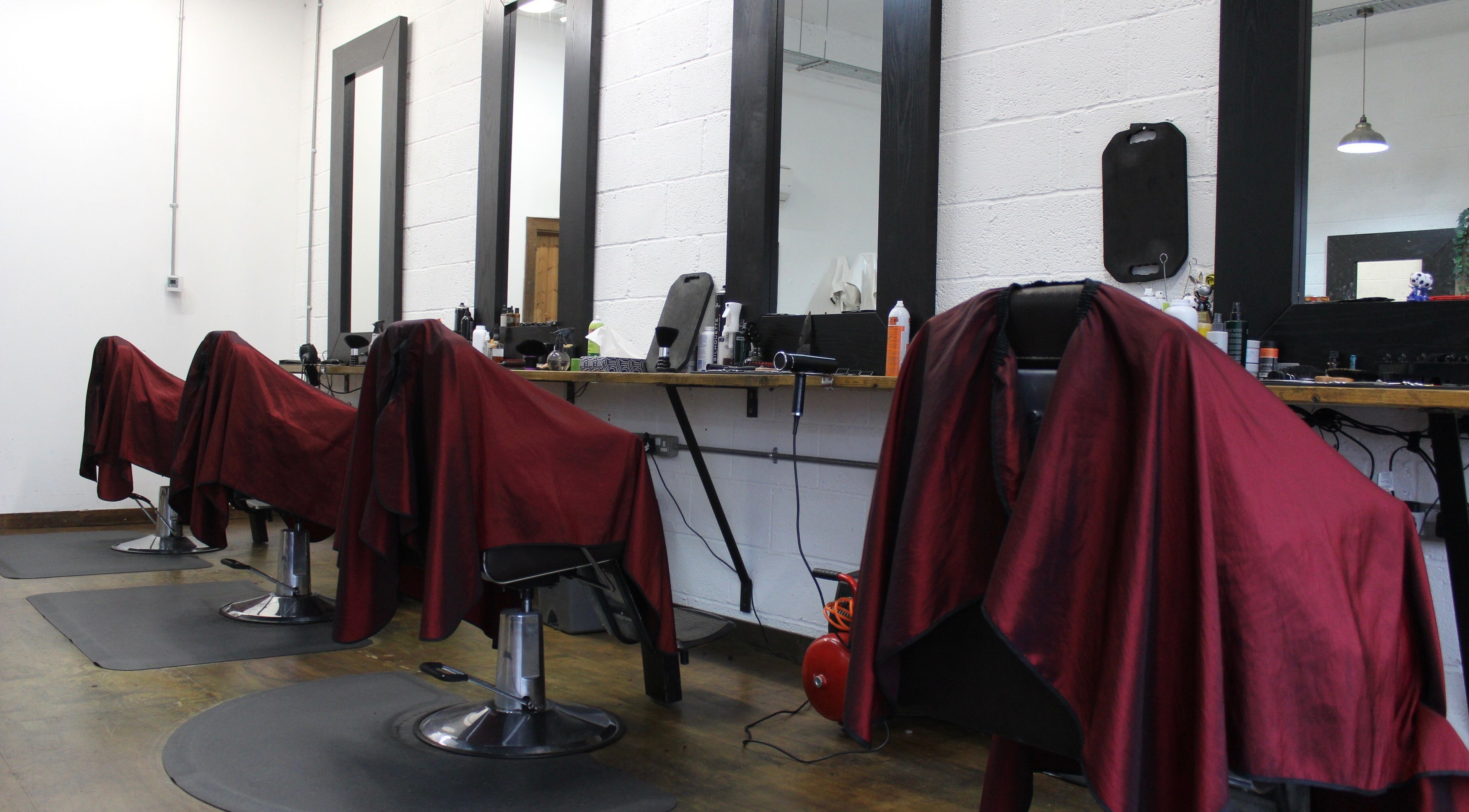 Interior of Lewis' Barbershop in Cambridge, England, GB showing stylish red-draped barber chairs.