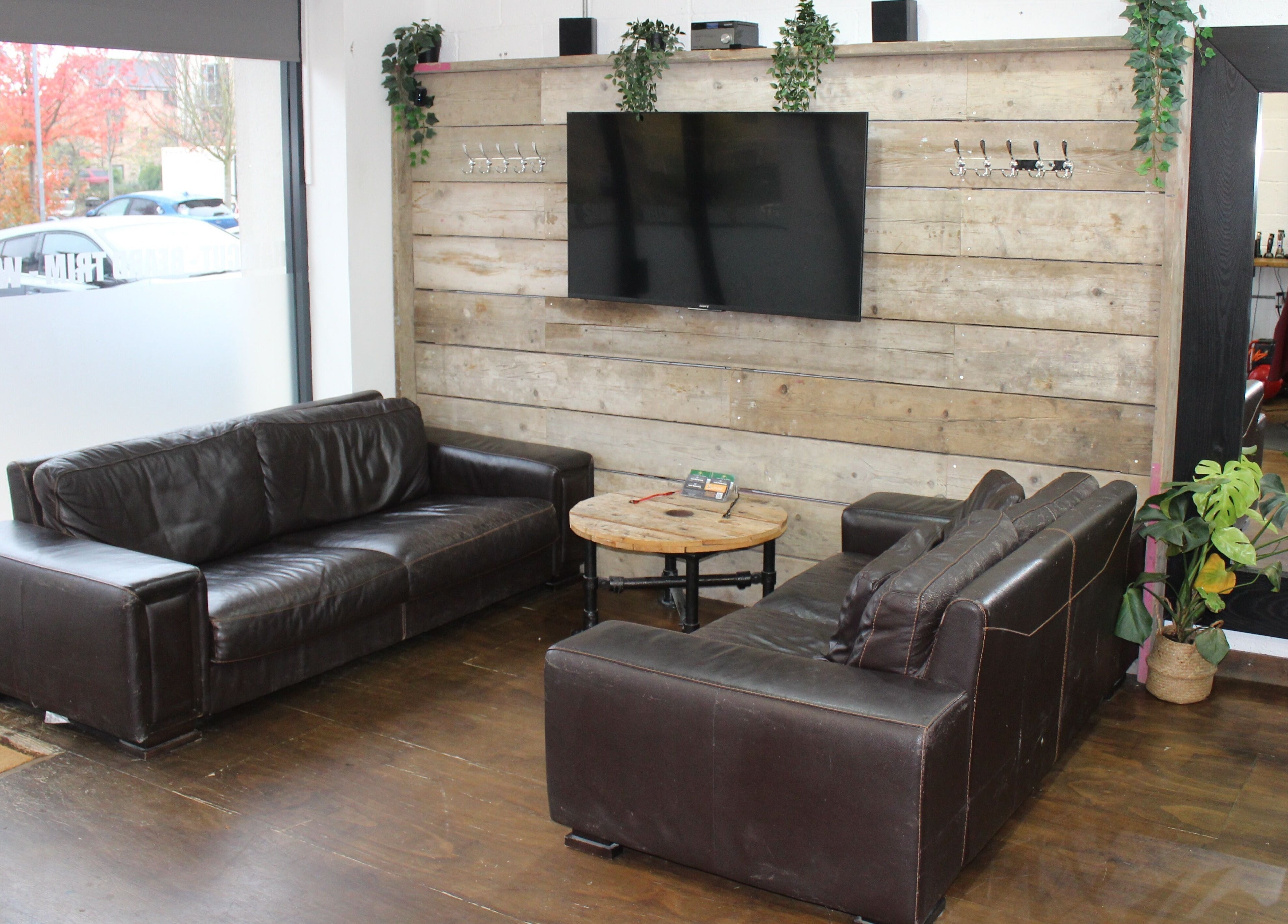 Cozy seating area inside Lewis' Barbershop, Cambridge, England, GB with stylish leather sofas.