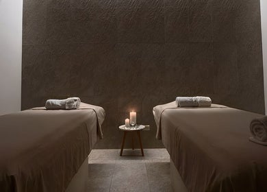 Tranquil massage room at Le Spa Noir, Medellín, Antioquia, CO, featuring two tables and ambient candlelight.