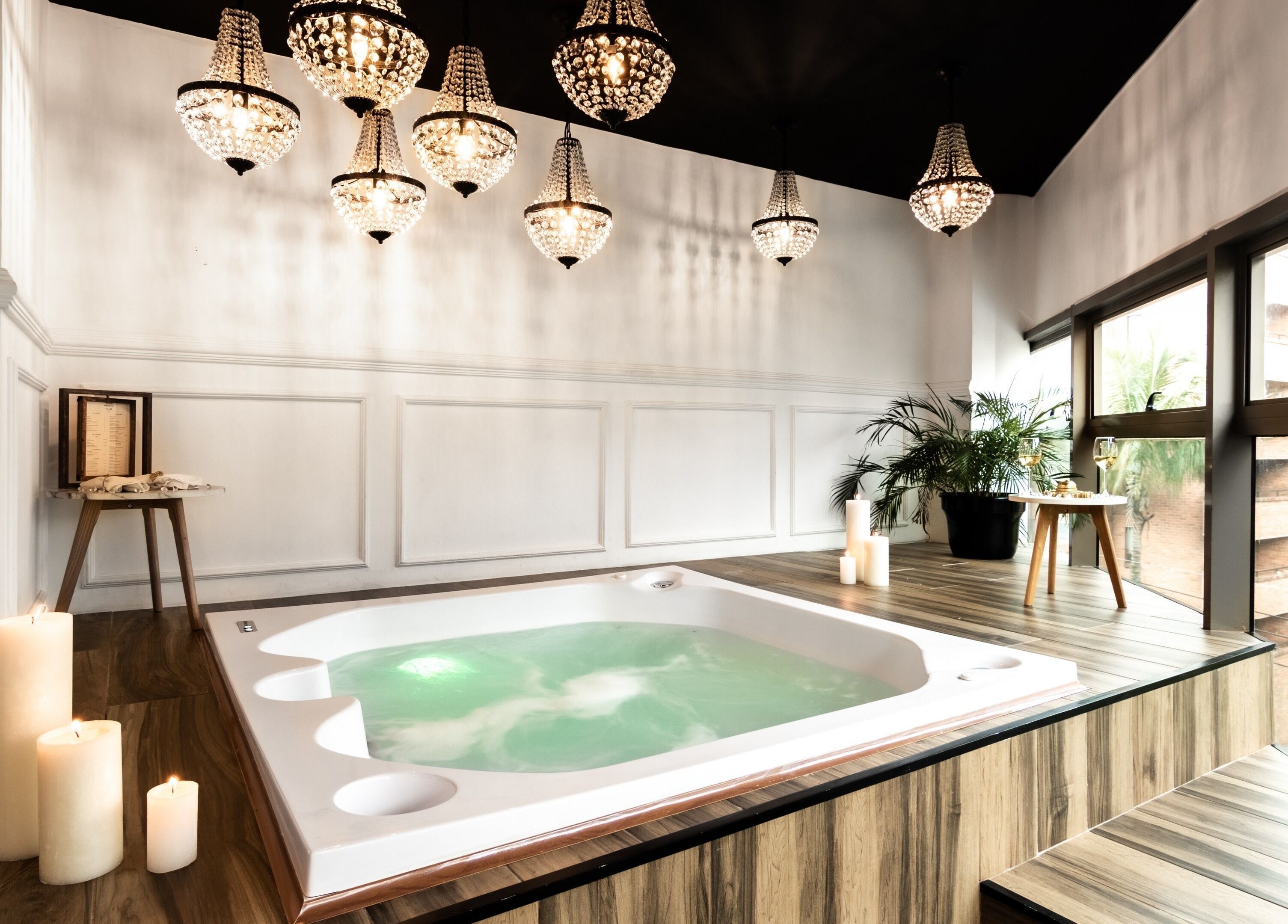Elegant spa room with hot tub at Le Spa Noir, Medellín, Antioquia, CO. Luxurious chandeliers and candles.