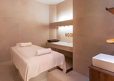 Tranquil massage room at Le Spa Noir in Medellín, Antioquia, CO, featuring a plush treatment bed and ambient lighting.