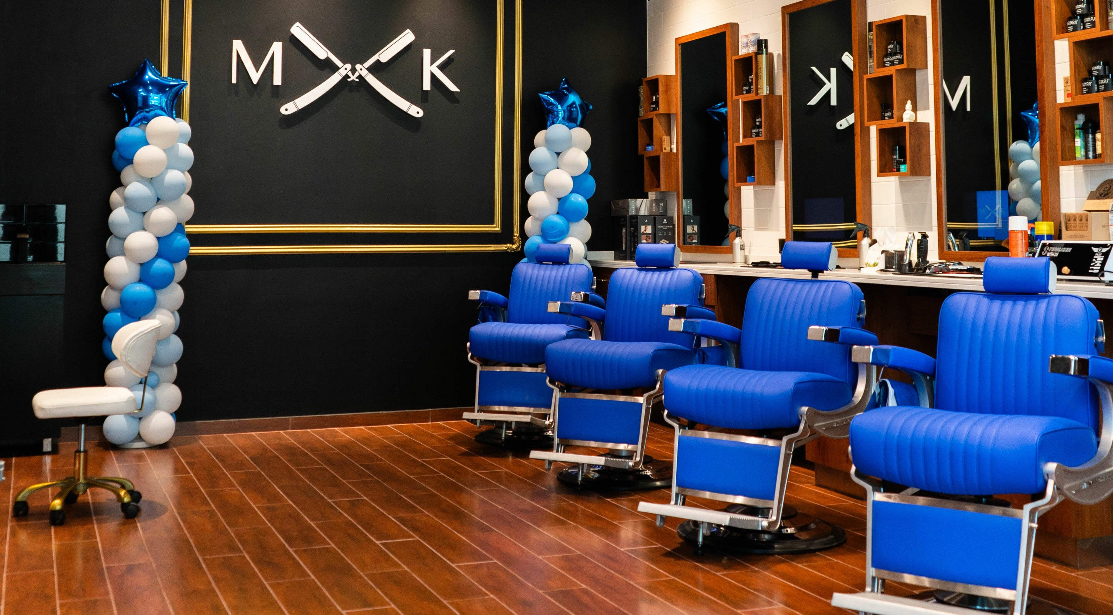 Spacious interior of MK Barbershop - NH Hotel The Palm Jumeirah, Dubai, with vibrant blue chairs and stylish decor.