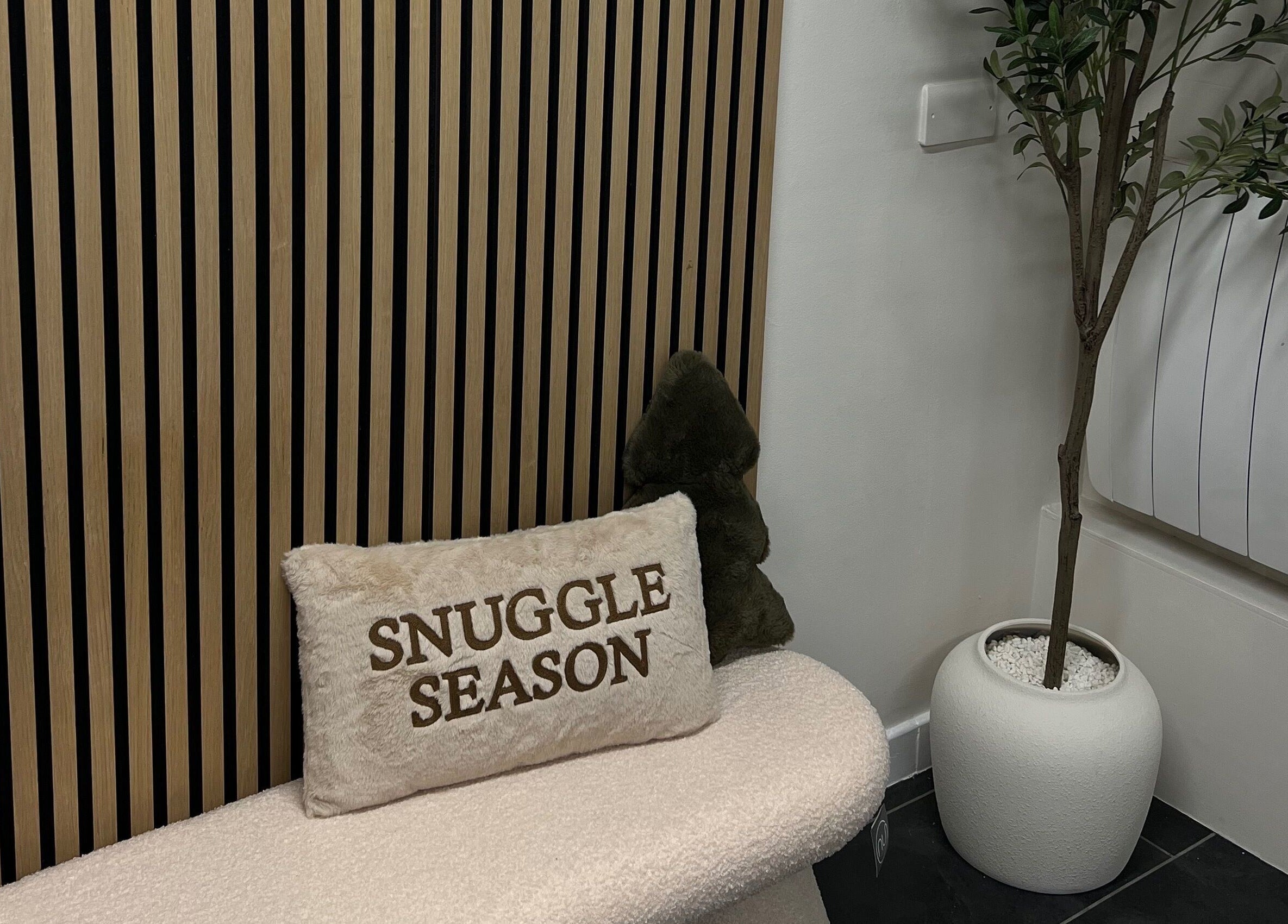 Cozy seating at Blush and Bloom Cosmetics, Nantwich, England, GB with pillows and a decorative plant.