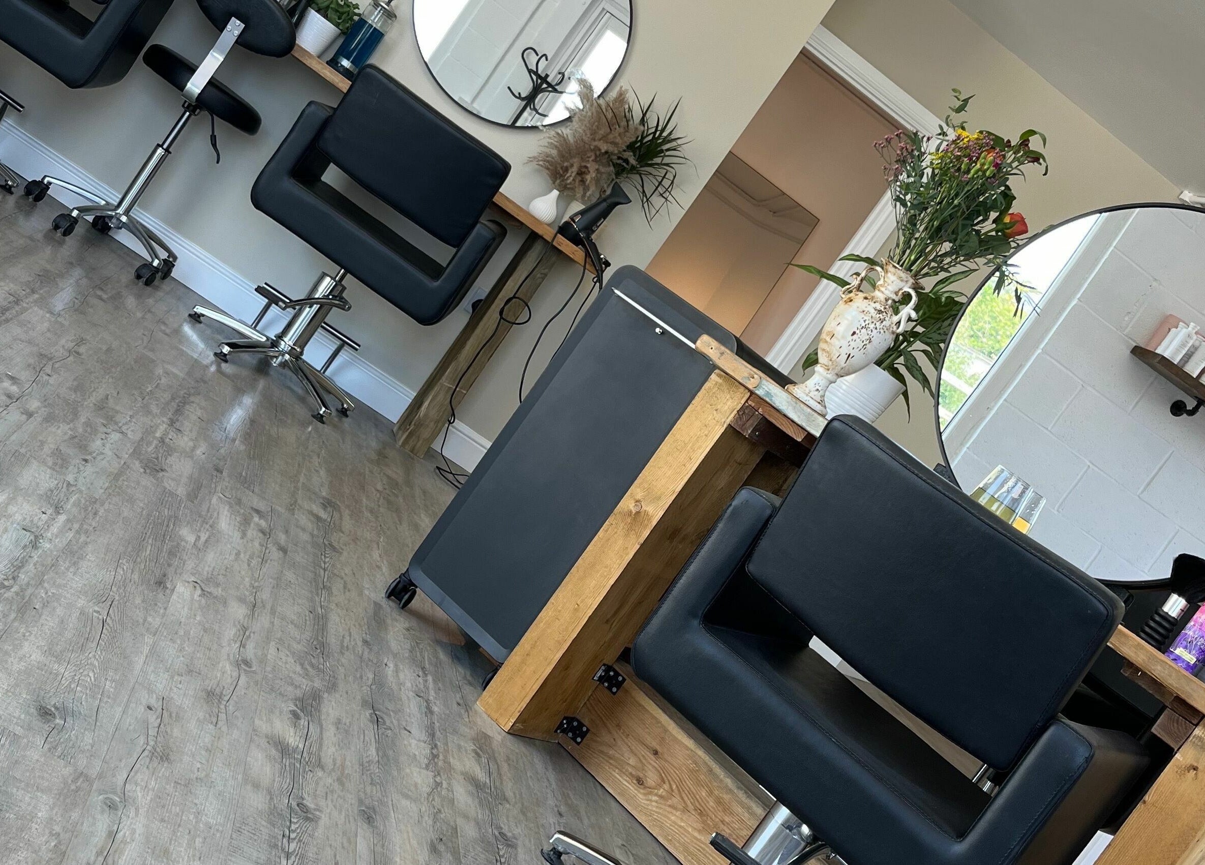 Modern interior of Stef Hayes Hair in Bude, England, GB, featuring sleek chairs and large mirrors.
