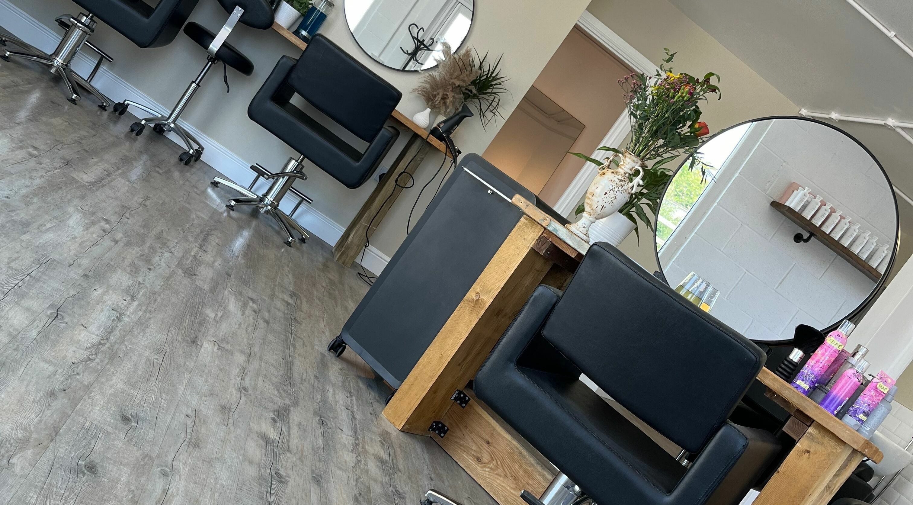Modern interior of Stef Hayes Hair in Bude, England, GB, featuring sleek chairs and large mirrors.