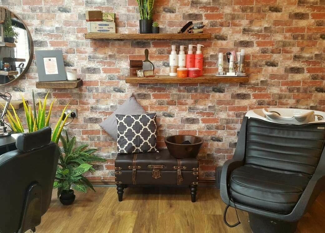 Stylish salon interior at Westgate Hair Lounge in York, England. Features cozy seating and rustic brick wall.