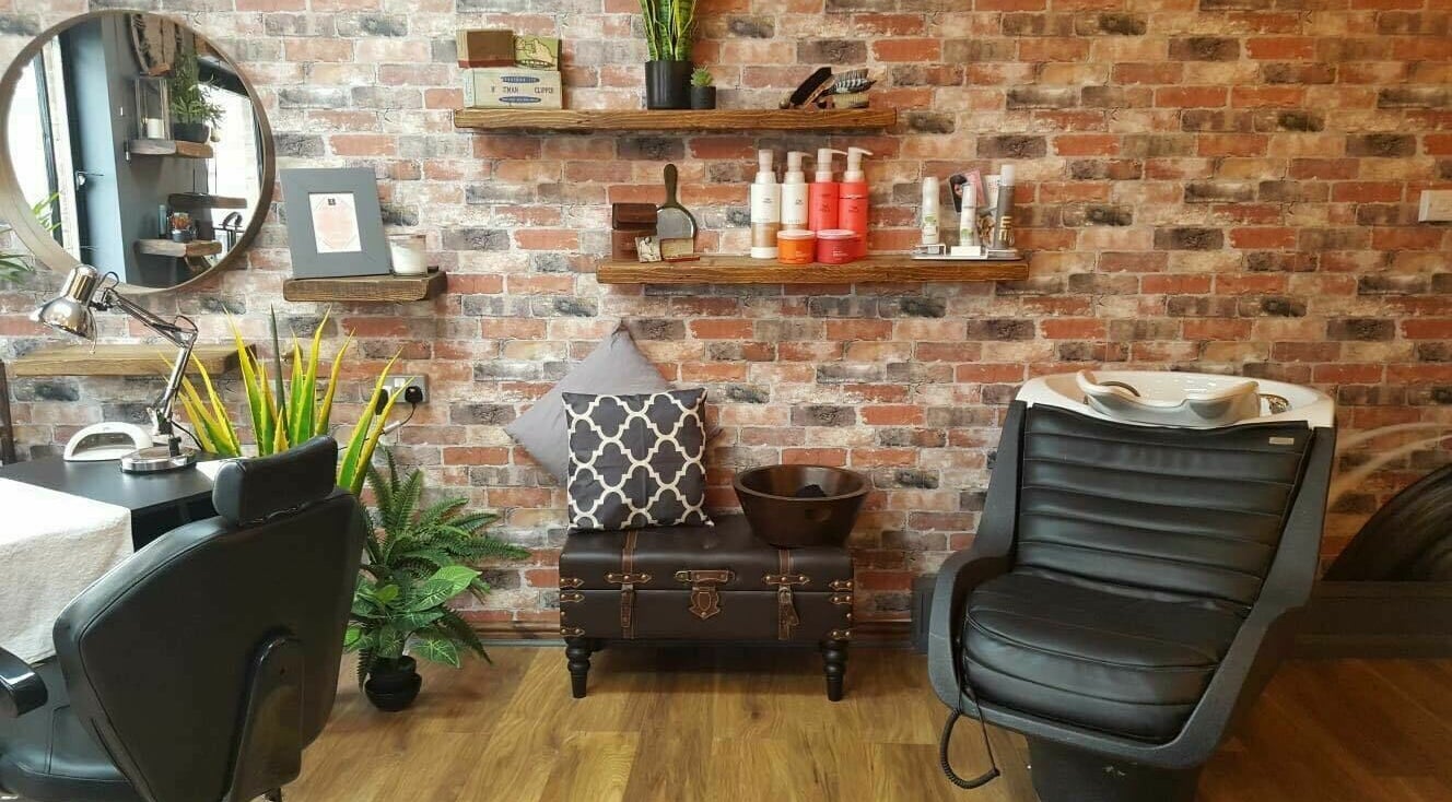 Stylish salon interior at Westgate Hair Lounge in York, England. Features cozy seating and rustic brick wall.