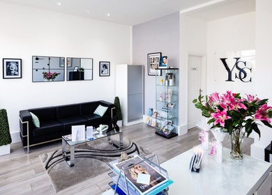 Elegant reception area at YSC Bournemouth & Online Clinic, Bournemouth, England, GB with black sofa and flowers.