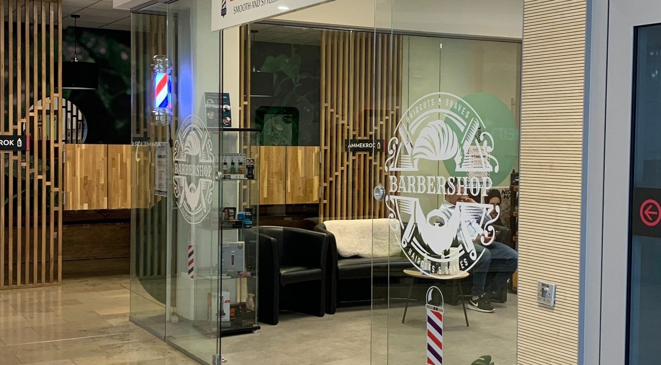 Moderne ingang til Mo's Barber i Oslo, Oslo, NO med glasspaneler og stilrent interiør.