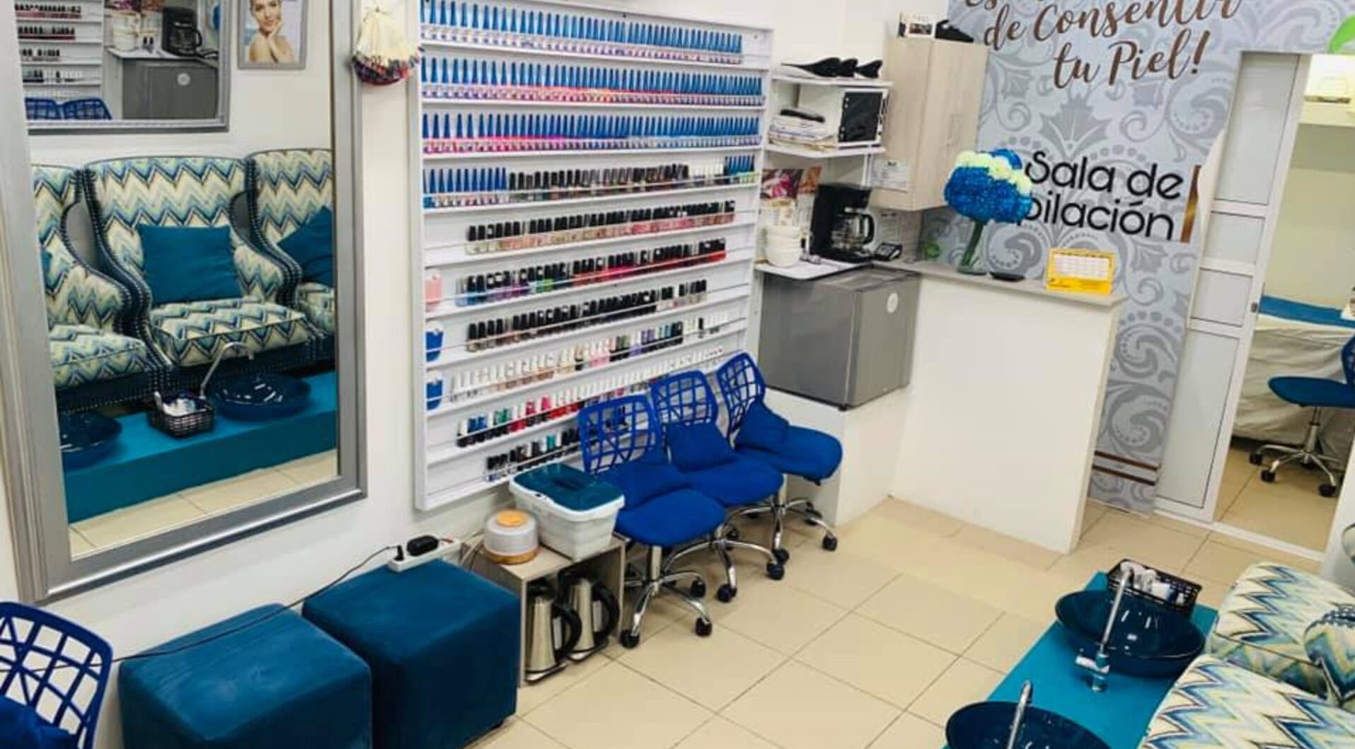 Interior de MG Spa de Uñas Manga en Cartagena, Bolívar, CO, mostrando sillas azules y estantes de esmaltes.