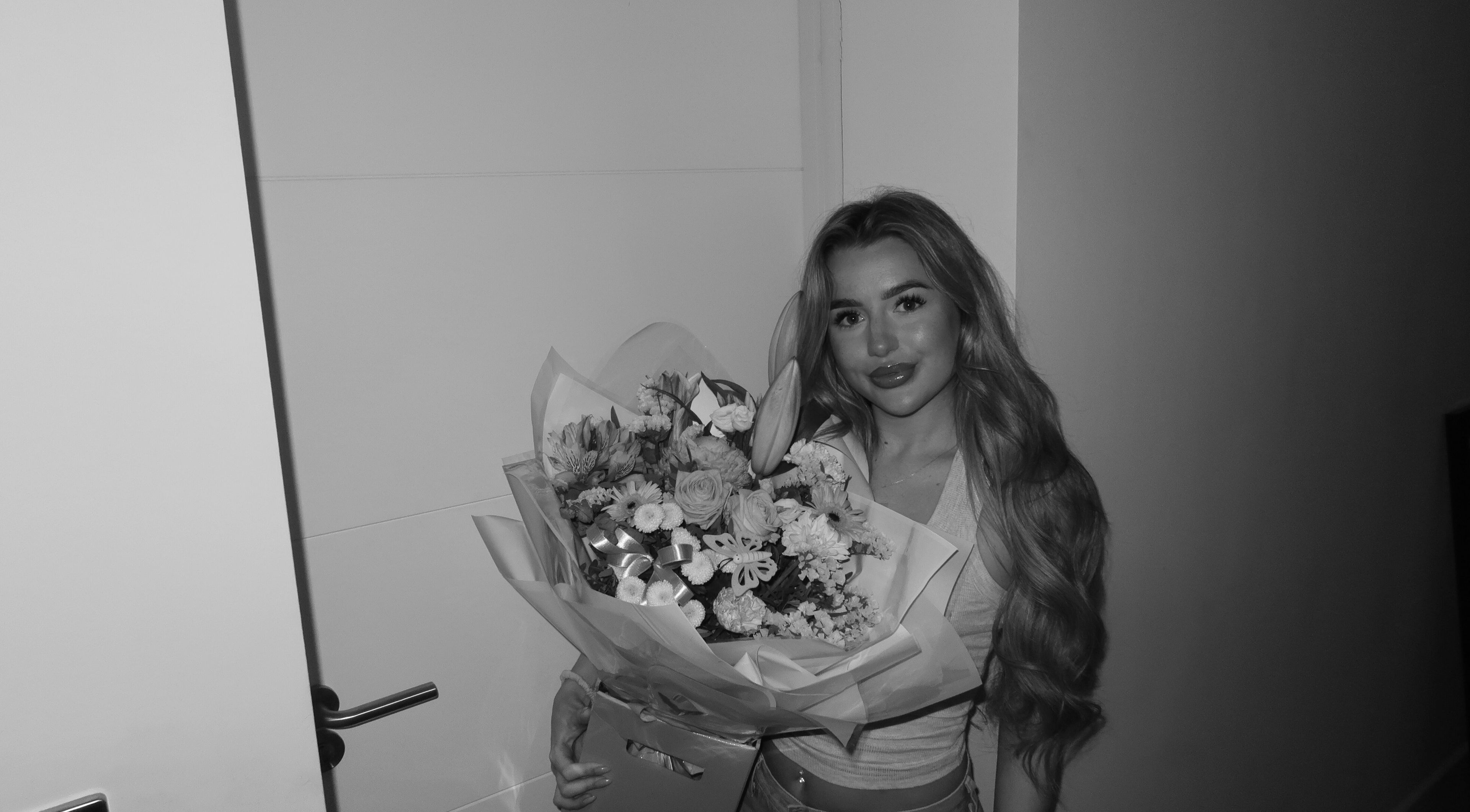 A woman holding a bouquet at By Summer Olivia, Birmingham, England, GB, showcasing floral beauty and wellness.