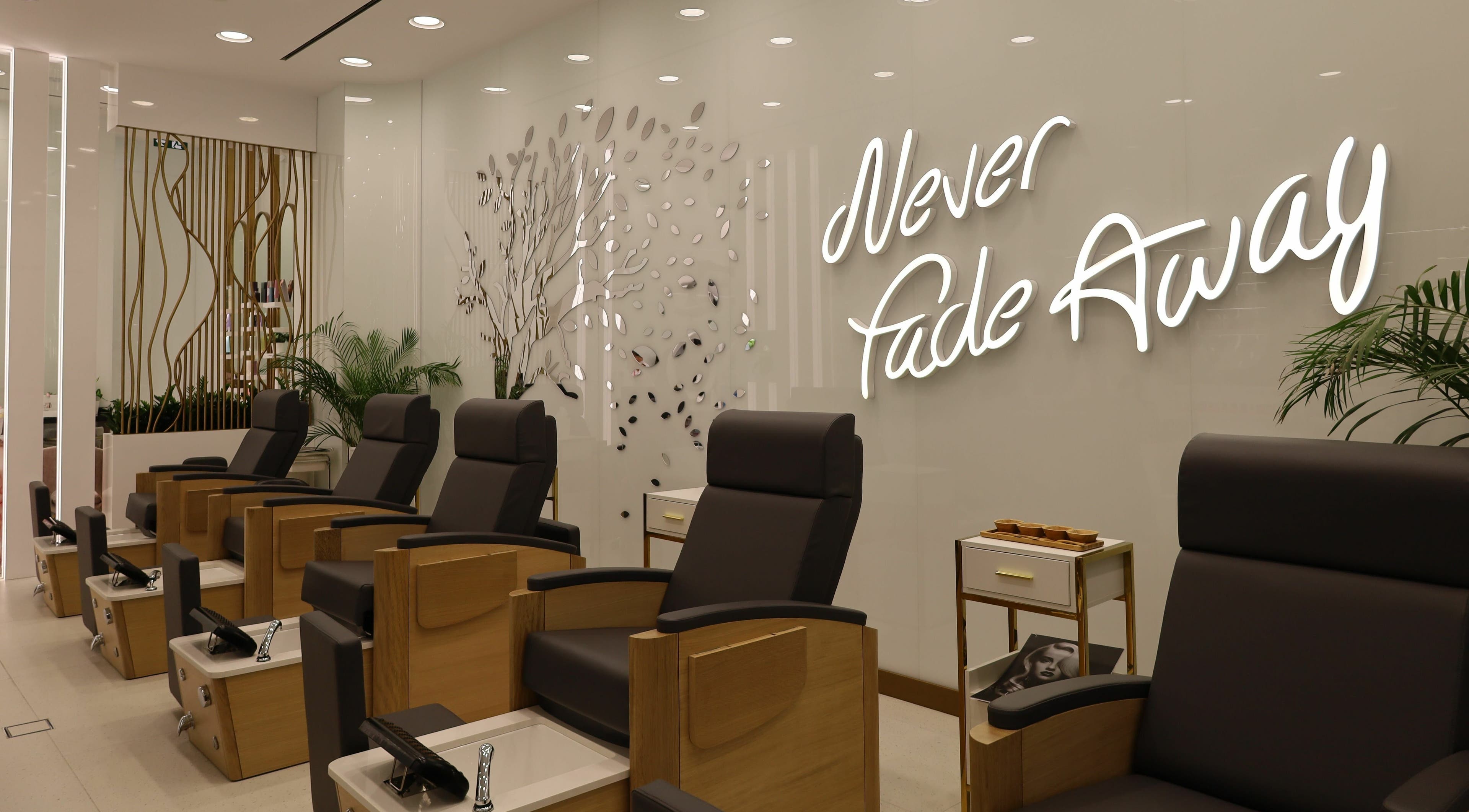 Chic pedicure chairs at WOW Beauty Salon Reem Mall, Abu Dhabi, AE, with modern decor and 'Never Fade Away' sign.