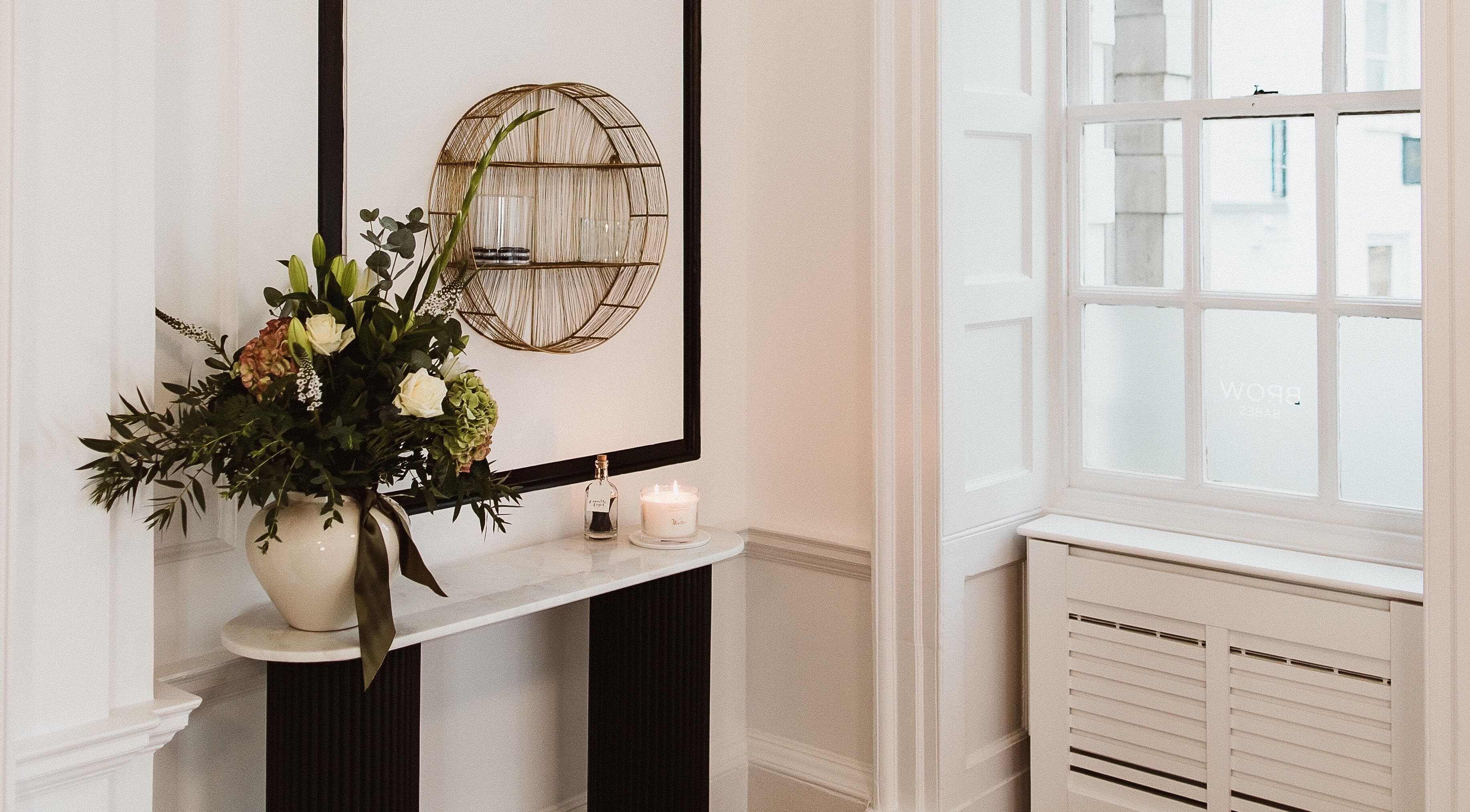 Chic interior at Brow Babes - Harry in Truro, England with elegant floral arrangement and candle.