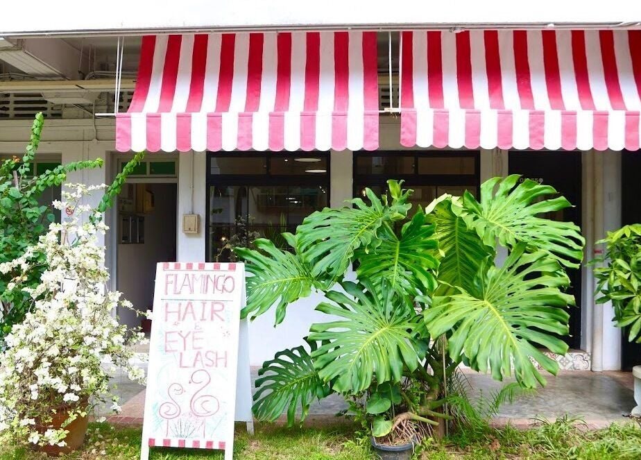 Charming entrance of Eyelash Studio Flamingo - Tiong Bahru, Singapore, SG, with lush greenery and red-striped awning.