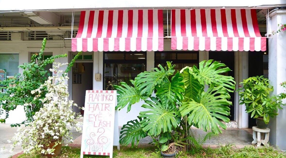 Charming entrance of Eyelash Studio Flamingo - Tiong Bahru, Singapore, SG, with lush greenery and red-striped awning.