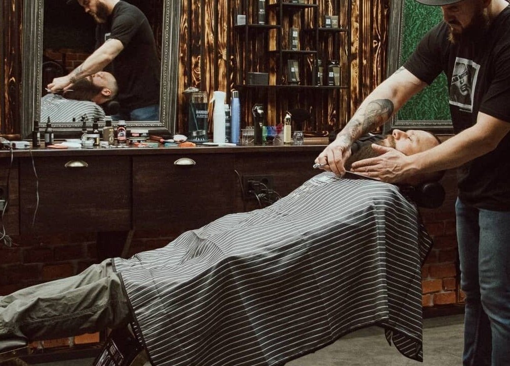 Barber expertly shaving a client at Alligator Barbers, Oslo, Oslo, NO with rustic decor.