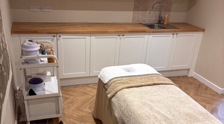 Cozy treatment room at Unwind Health and Beauty, Portsmouth, England, GB with massage table and wooden cabinets.