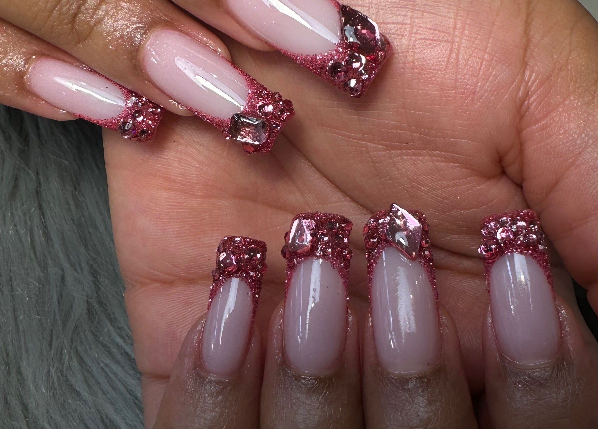Close-up of glam glitter nail art at Rose Nails, Barking, England, GB. Sparkling pink designs shine brightly.