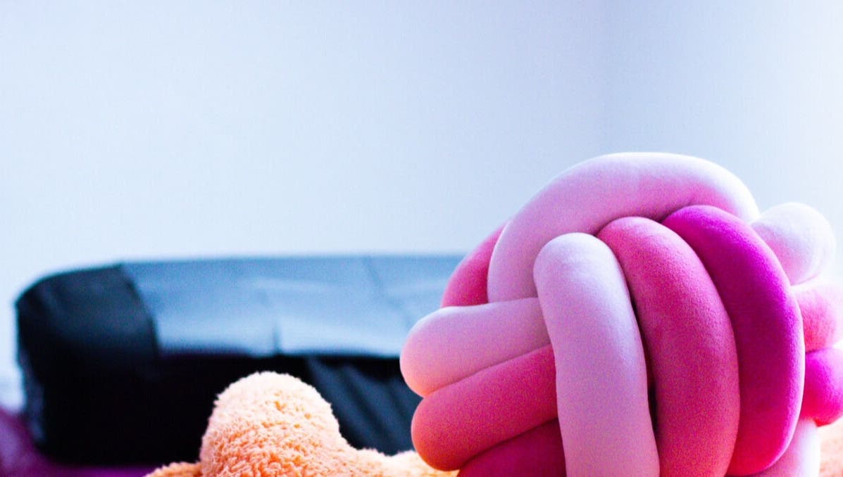 Plush pink and orange knot pillow in Gee’s Beauty Gloucester, Gloucester, England, GB spa room.