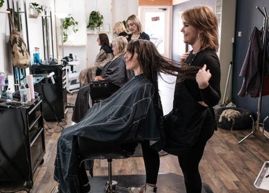 Stylist in Salon X, Taos, New Mexico, US, working on a client's hair, enhancing beauty and relaxation.