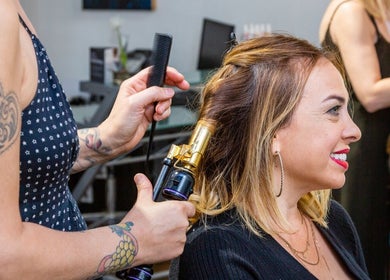 Stylist curling hair at Salon X. Elegant hair service in Taos, New Mexico. Vibrant look transformation.