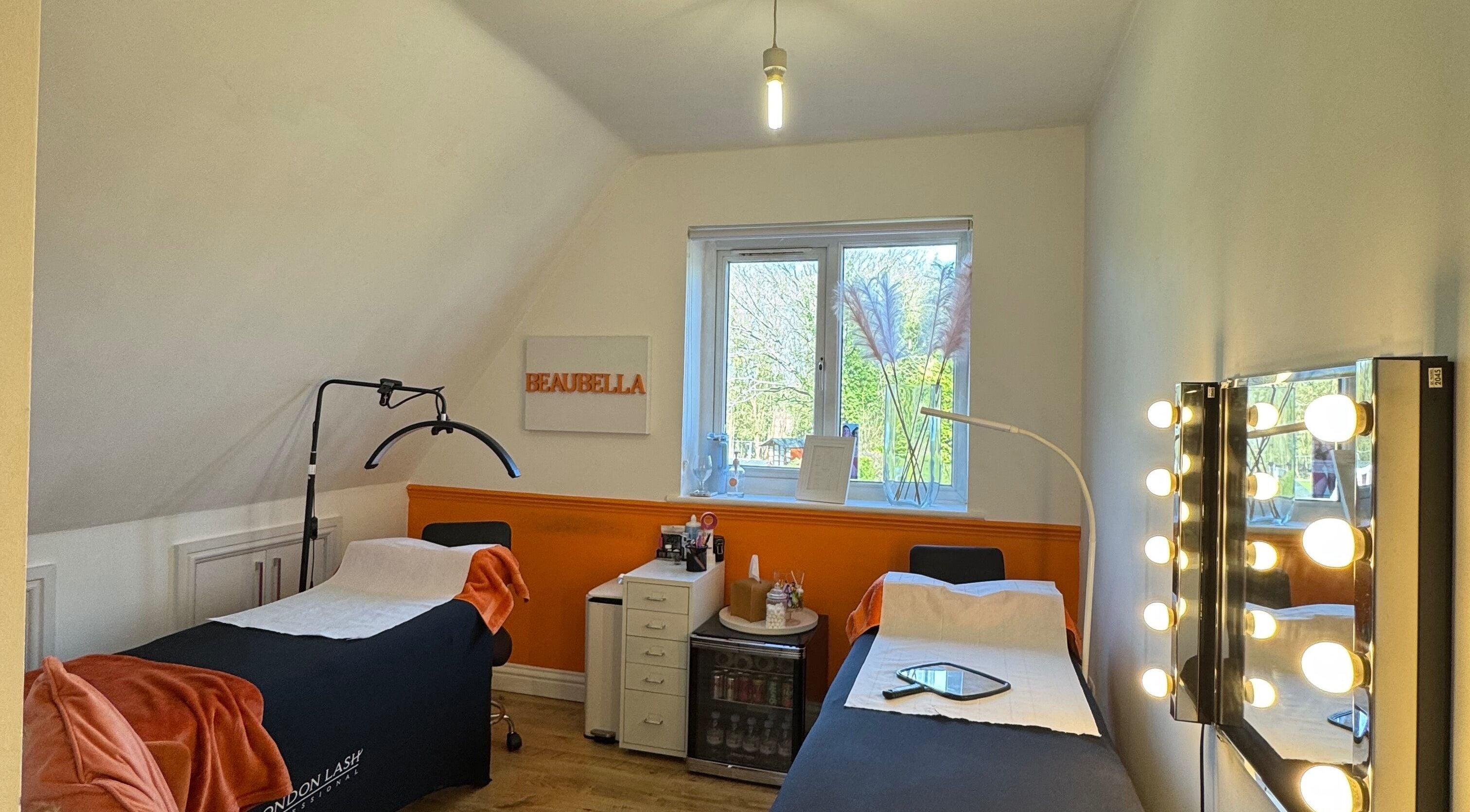 Cozy beauty room at Beaubella in Bishops Stortford, England, GB, with treatment beds and bright vanity mirrors.