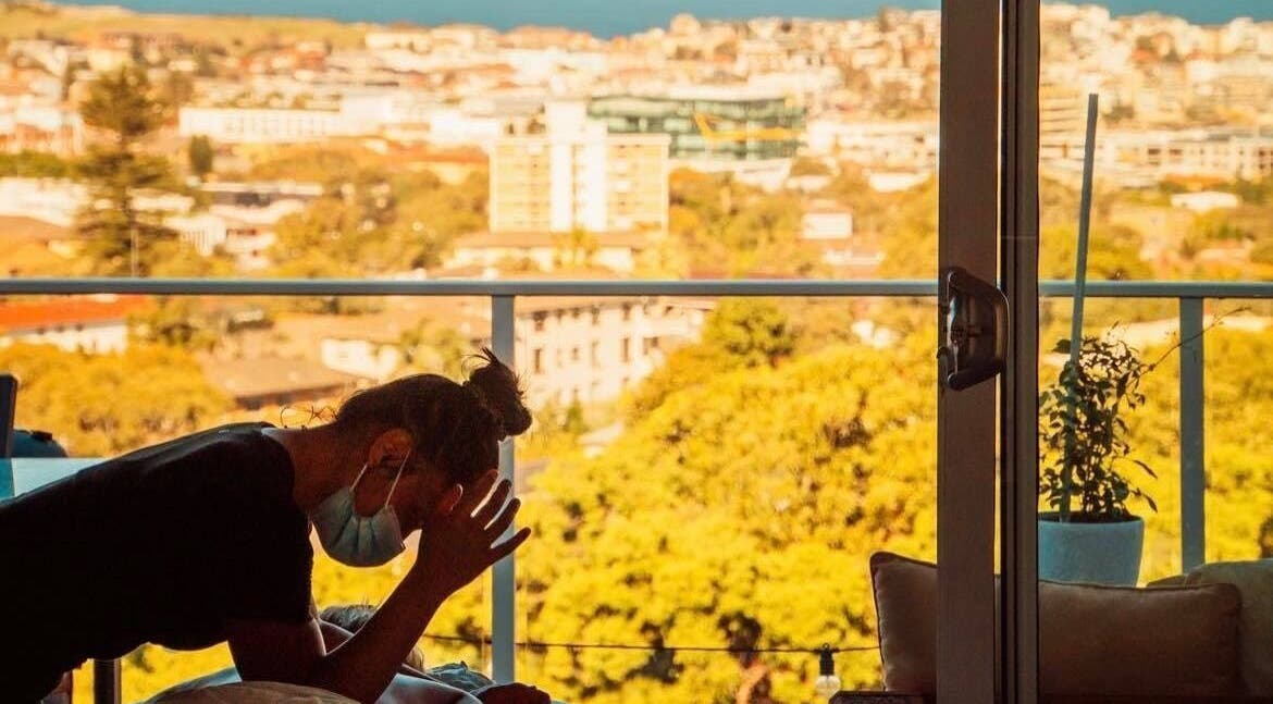 Therapist at Minty Massage (Home visit) provides chair massage with Sydney skyline view in Bondi Junction, New South Wales, AU.