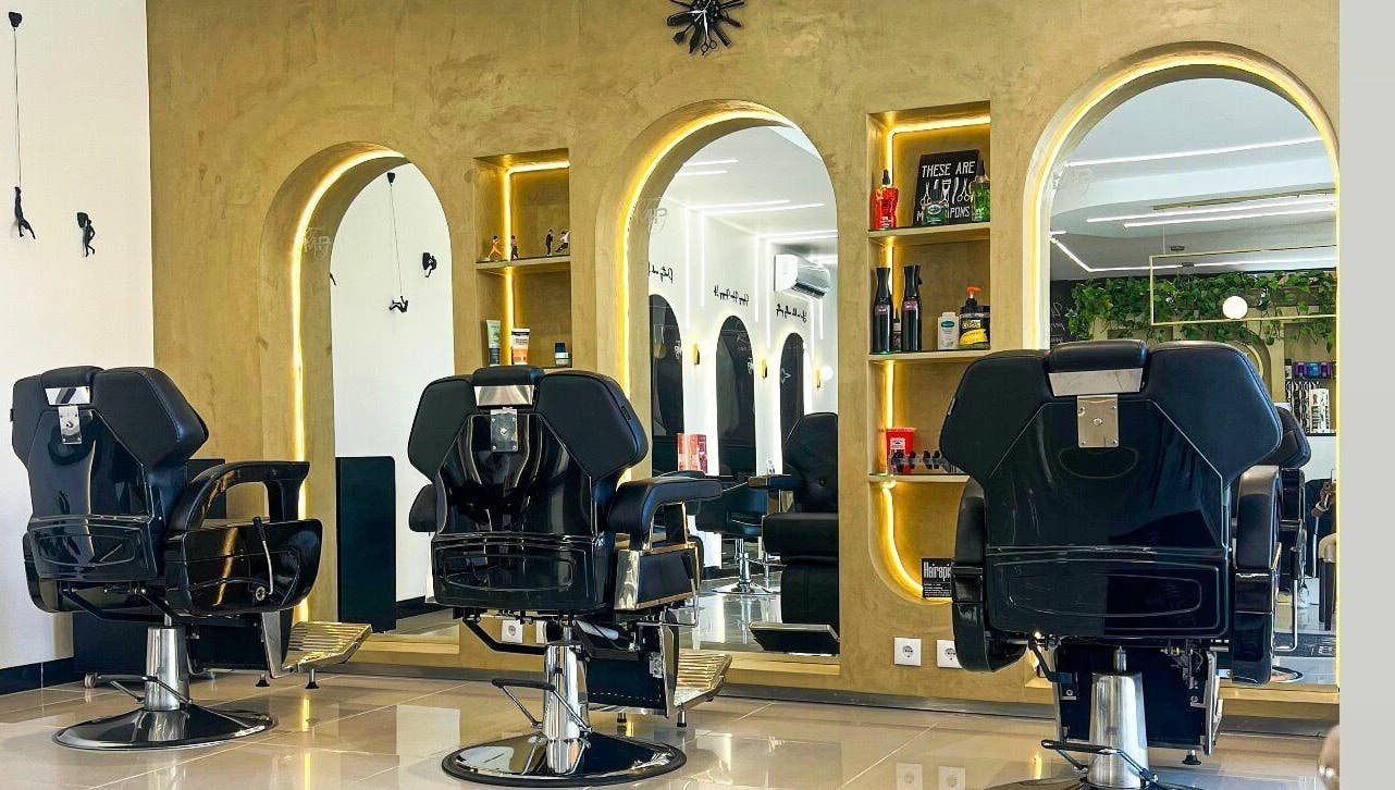 Interior elegante do The Mani Pedi Spa Maputo com cadeiras pretas e espelhos sofisticados em Maputo, Maputo, MZ.