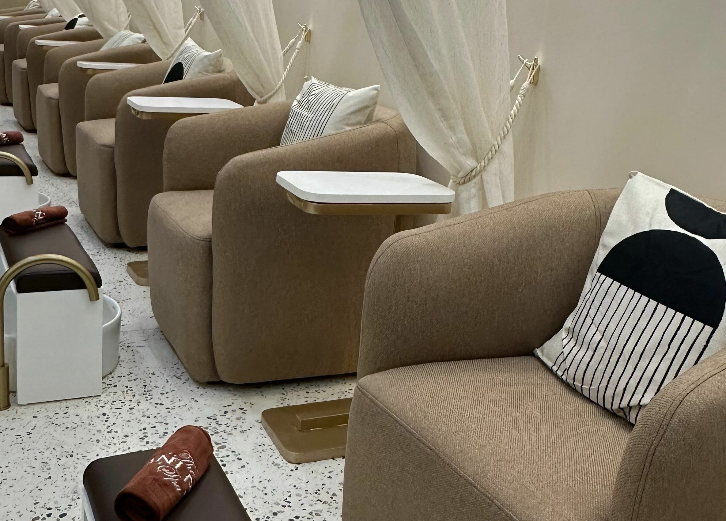 Área de relaxamento no The Mani Pedi Spa Maputo, Maputo, MZ, com poltronas confortáveis e bacias de pedicure.