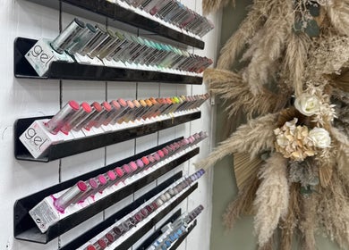 Colorful nail polish display at Nails by Lia in Wednesbury, England, GB next to elegant floral decor.