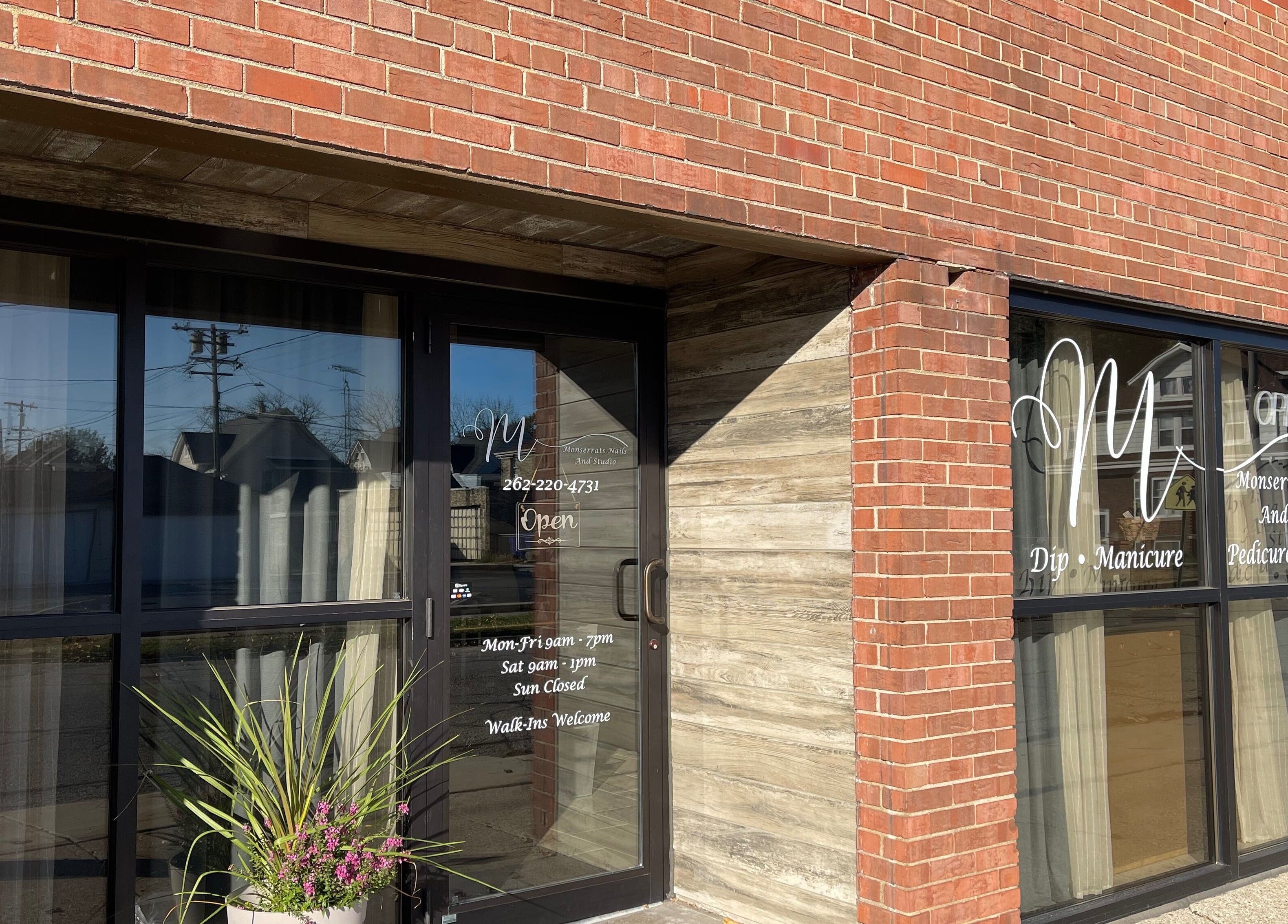 Front entrance of Monserrat Nails in Kenosha, Wisconsin, US with brick exterior and glass door.