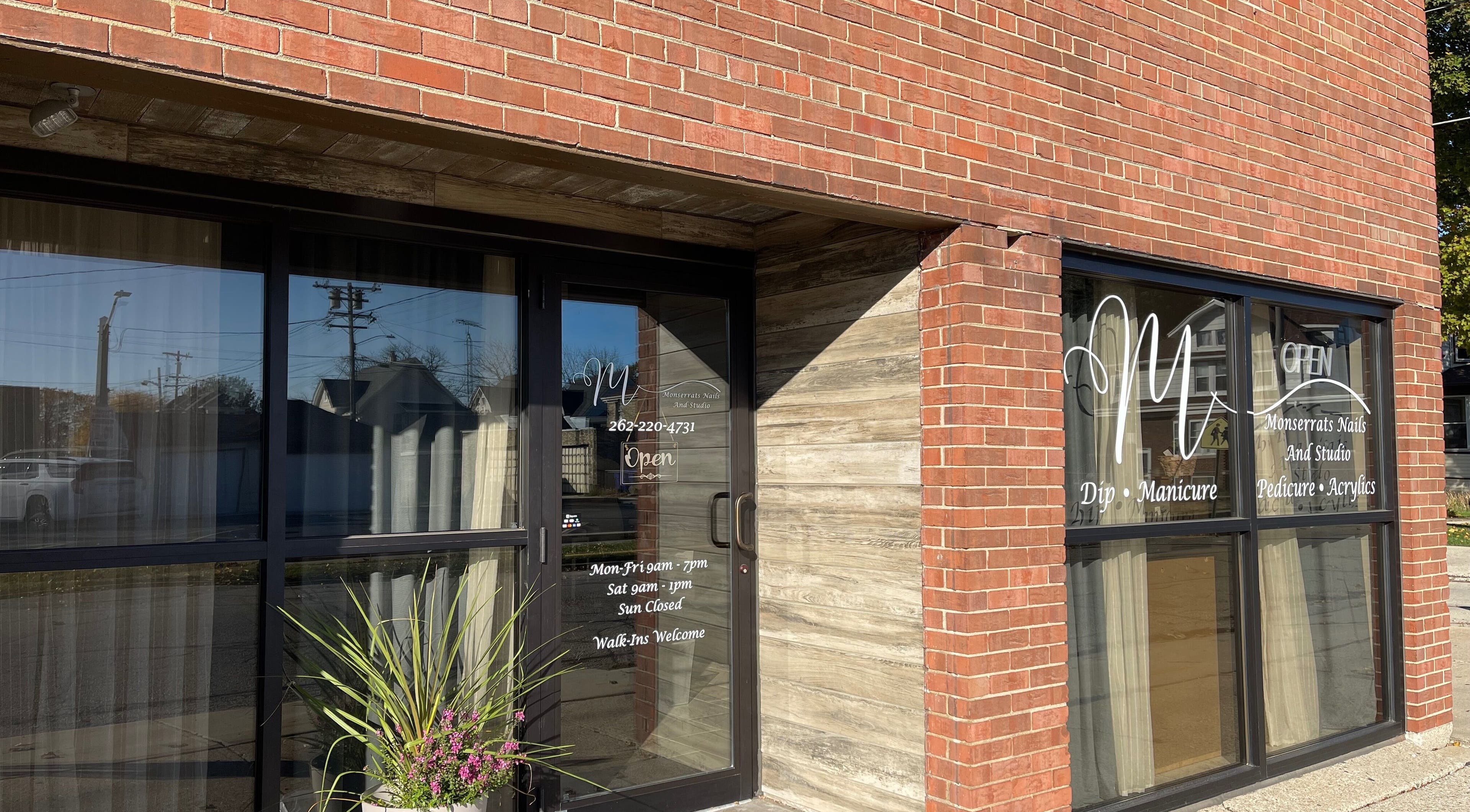 Front entrance of Monserrat Nails in Kenosha, Wisconsin, US with brick exterior and glass door.