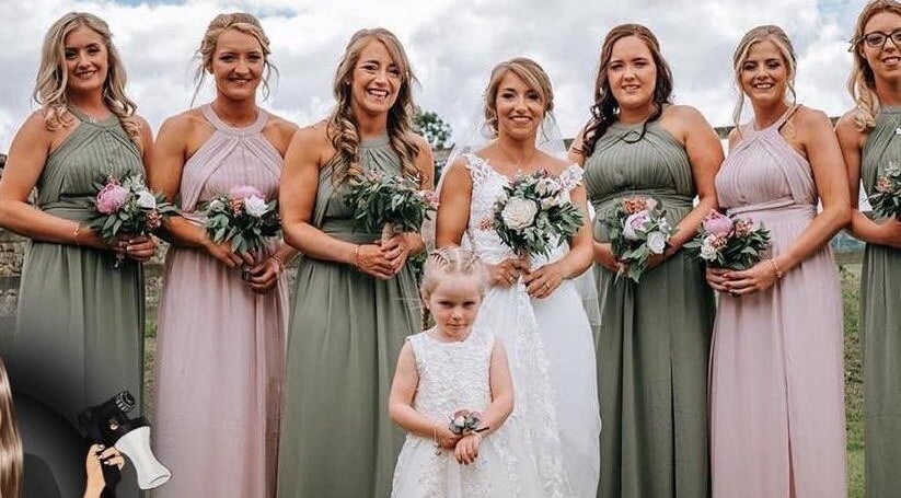 Bridal party smiling outdoors at The Tanning Room, Hall Green, England, GB, celebrating with bouquets.