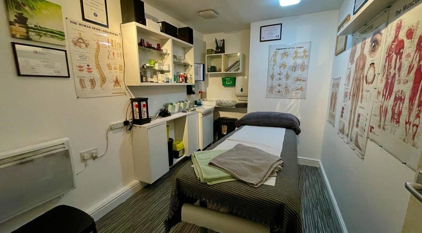 Therapy room in Yakushi Healing Centre, Sandiacre, England, GB featuring massage bed and anatomical charts.