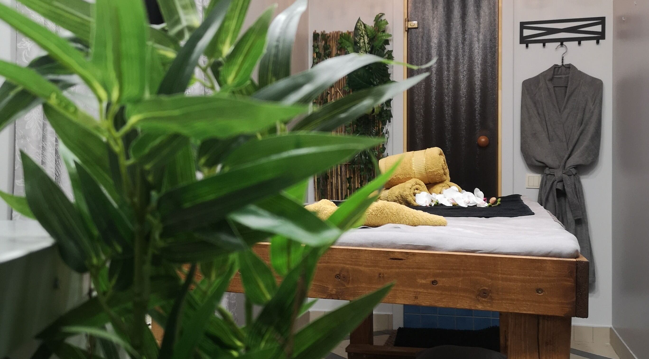Relaxing massage room at Asia Spa Thai Massage in Rīga, LV with a cozy robe and tropical plants.