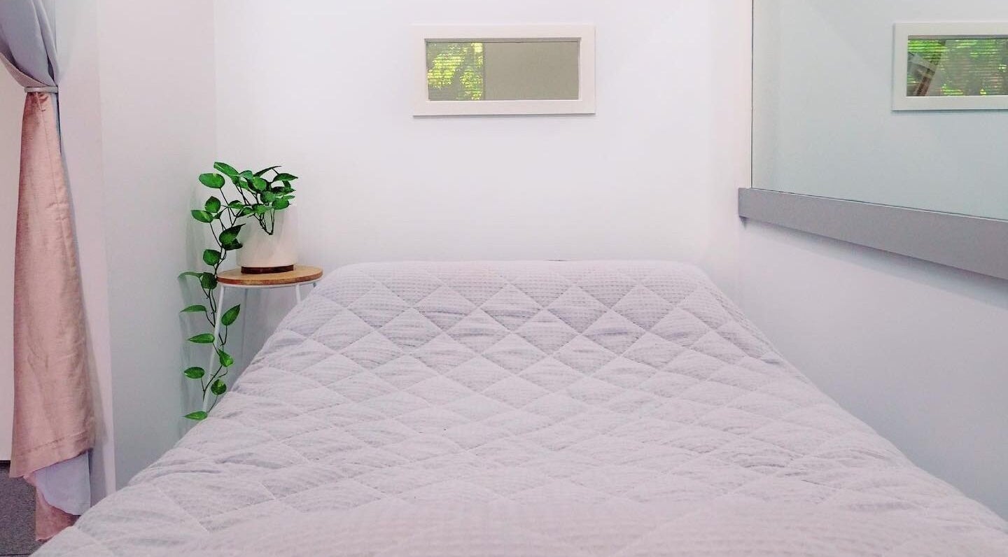 Calm treatment room at Lash Laine, Robina, Queensland, AU with a plush bed and plant decor.