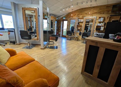 Stylish salon interior at Essence, Bourton-on-the-Water, England, GB with modern chairs and orange couch.