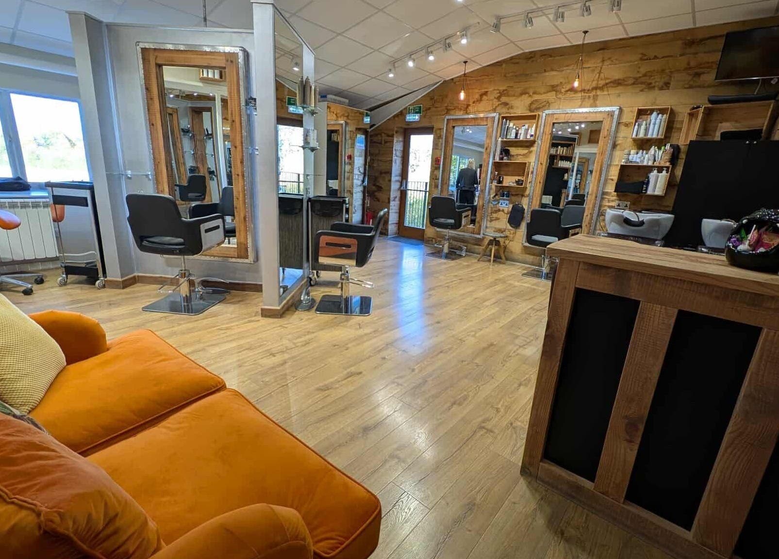 Stylish salon interior at Essence, Bourton-on-the-Water, England, GB with modern chairs and orange couch.